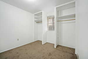 Unfurnished bedroom featuring carpet flooring and two closets