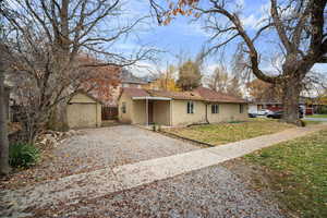 View of property exterior featuring a yard, a shed, brick siding, driveway, and a shingled roof