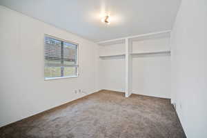 Unfurnished bedroom with light colored carpet and two closets