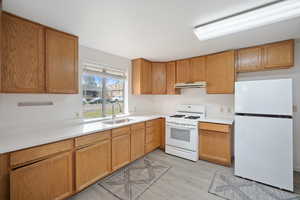 Kitchen featuring white appliances, light countertops, light wood-type flooring, and under cabinet range hood