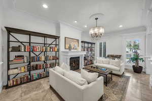 Living area featuring ornamental molding, a glass covered fireplace, a chandelier, and recessed lighting