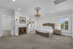 Bedroom with ornamental molding, carpet floors, access to outside, a fireplace, and a chandelier