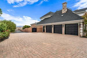 View of home's exterior with a gate, decorative driveway, a shingled roof, and an attached garage