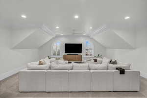 Home theater with light carpet, ornamental molding, recessed lighting, lofted ceiling, and a ceiling fan