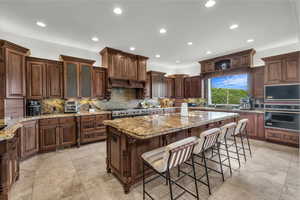 Kitchen with light stone countertops, tasteful backsplash, a breakfast bar area, a kitchen island, and recessed lighting