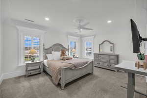 Carpeted bedroom with multiple windows, ornamental molding, ceiling fan, and recessed lighting