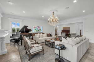 Living area featuring a fireplace with raised hearth, crown molding, a chandelier, recessed lighting, and light tile patterned flooring