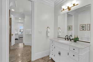 Ensuite bathroom with crown molding, vanity, and light tile patterned flooring