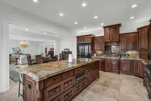 Kitchen with dark stone counters, backsplash, recessed lighting, a center island, and high end appliances