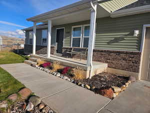Property entrance featuring covered porch and brick siding
