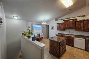 Kitchen featuring arched walkways, dark brown cabinetry, dishwasher, vaulted ceiling, and a kitchen island
