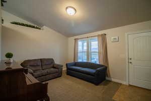 Living area featuring vaulted ceiling, carpet floors, and a textured ceiling