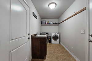 Laundry room with a textured ceiling and washer and clothes dryer