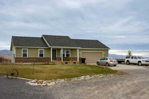 Ranch-style house with driveway, a mountain view, covered porch, brick siding, and a front lawn