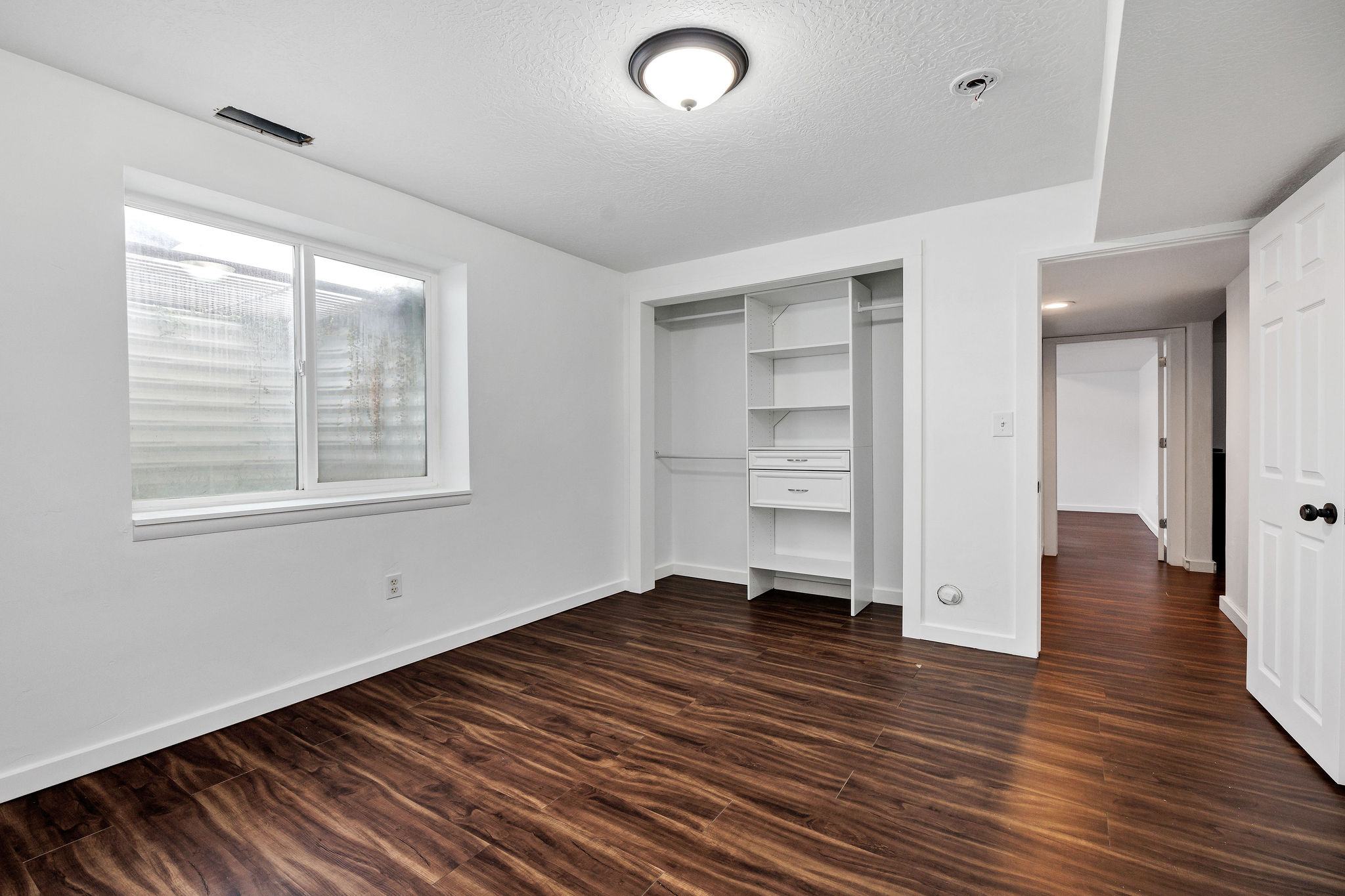 Unfurnished bedroom with dark wood-type flooring, a closet, and a textured ceiling