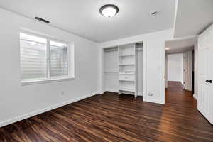 Unfurnished bedroom with dark wood-type flooring, a closet, and a textured ceiling