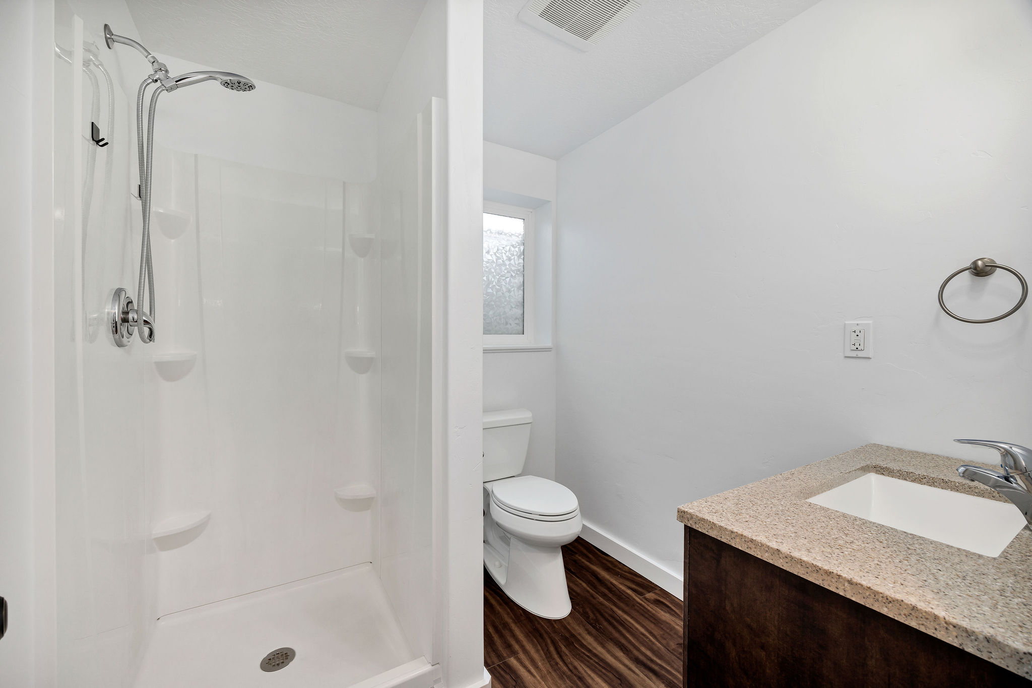 Bathroom featuring dark wood-style flooring, vanity, and a stall shower