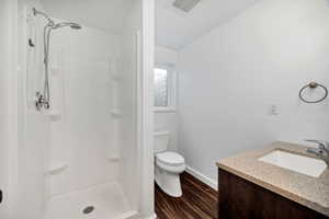 Bathroom featuring dark wood-style flooring, vanity, and a stall shower