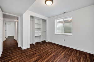 Unfurnished bedroom featuring dark wood-type flooring, a closet, and a textured ceiling