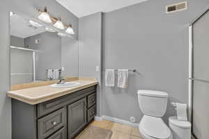 Bathroom with a shower stall, light tile patterned floors, and vanity