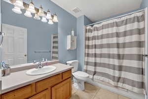 Full bathroom featuring light tile patterned floors, vanity, a textured ceiling, and shower / bathtub combination with curtain