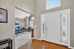Foyer entrance with high vaulted ceiling and wood finished floors