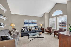 Carpeted living area with high vaulted ceiling and baseboards