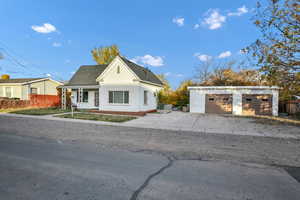 Bungalow-style house with an outbuilding, a garage, roof with shingles, stucco siding, and covered porch