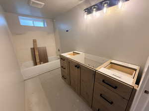 Bathroom with concrete floors, vanity, and a textured ceiling