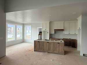 Kitchen with a kitchen island, white cabinetry, brown cabinetry, and recessed lighting