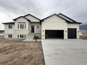 View of front of house featuring stone siding, a garage, driveway, and board and batten siding