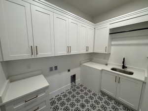 Laundry area with hookup for a washing machine, light flooring, hookup for an electric dryer, and cabinet space