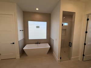 Bathroom with plenty of natural light, a shower stall, a freestanding bath, and tile patterned flooring