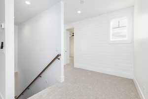 Corridor with an upstairs landing, carpet, and recessed lighting