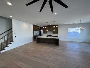 Kitchen featuring open floor plan, dark brown cabinetry, dark wood-style floors, decorative light fixtures, and recessed lighting