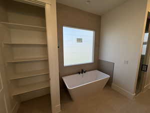 Bathroom with a freestanding tub, light tile patterned floors, and a shower stall