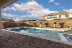 View of pool with a fenced backyard, a patio area, and a pool with connected hot tub