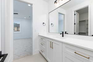 Bathroom featuring light colored carpet, vanity, a spacious closet, light tile patterned flooring, and recessed lighting