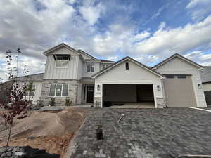 Craftsman-style house featuring stone siding, board and batten siding, an attached garage, and decorative driveway