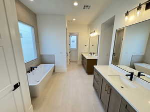 Bathroom featuring a soaking tub, two vanities, recessed lighting, light tile patterned floors, and a stall shower