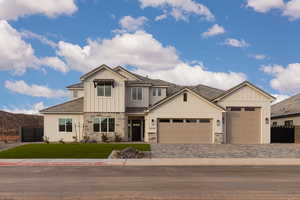 Craftsman house with stone siding, a garage, board and batten siding, and decorative driveway