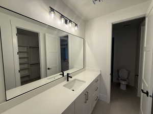 Full bathroom with vanity, light tile patterned floors, and a spacious closet