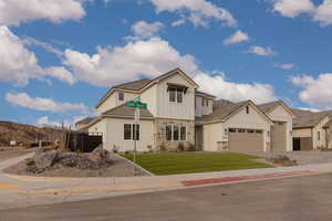 View of front of property featuring an attached garage, stone siding, decorative driveway, and board and batten siding