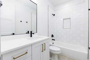 Full bath featuring washtub / shower combination, vanity, and light tile patterned flooring