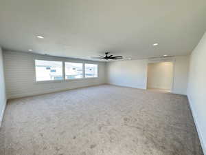 Empty room featuring carpet flooring, recessed lighting, wood walls, and ceiling fan