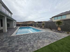 View of pool featuring a fenced backyard, a patio, a pool with connected hot tub, and a mountain view