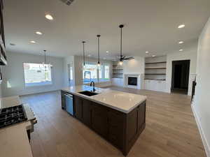 Kitchen with a fireplace, open floor plan, dark brown cabinets, decorative light fixtures, and recessed lighting