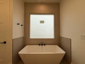 Full bathroom featuring a freestanding tub and tile walls