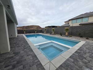 View of pool with a fenced backyard, a patio, and a pool with connected hot tub