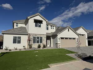 Craftsman-style house featuring decorative driveway, stone siding, a front yard, a garage, and board and batten siding